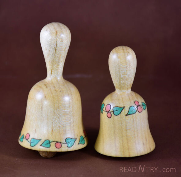 Two bells turned from maple and embellished with leaves and berries.
