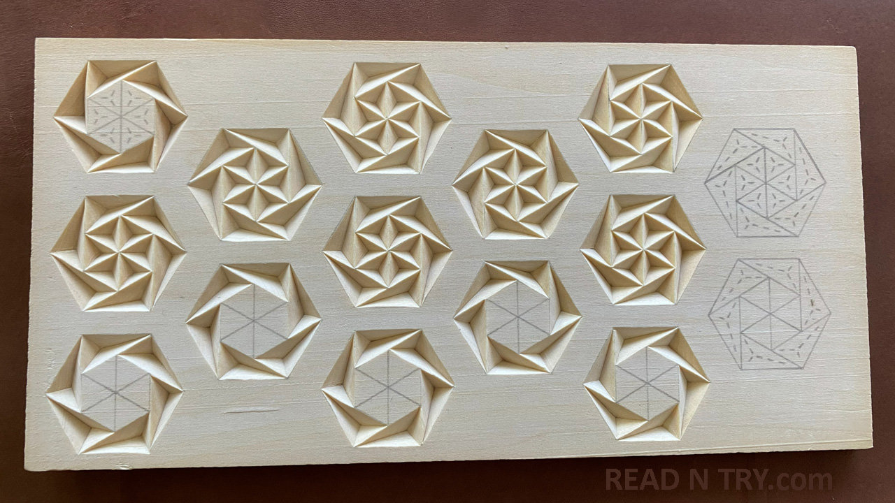 A basswood board with the Pinwheel chip carving patterns. Most pinwheels are carved, and two are left uncarved for the photo. It shows that it is easy to carve many at once on a board, then separate them later to make small ornaments or fridge magnets.