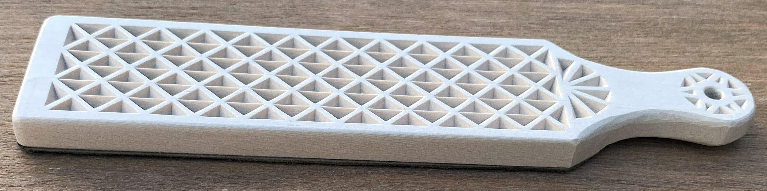 A DIY strop with a simple chip-carving pattern on one side and leather on the other. Made from 3/8" basswood board by Roman Chernikov.